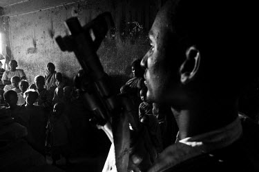 An armed security guard stands among a crowd of people at Badbaado, one of the many camps for IDPs (internally displaced persons) that have sprung up in and around the city. The Horn of Africa is curr...