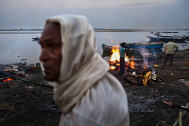 A mourning son (left) looks on while the pyre of one of his parents burns in the background at the Harishchandra Ghat in the ancient city of Varanasi.