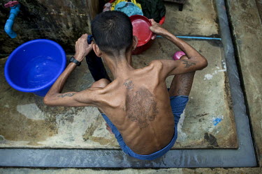 An HIV positive patient with tattoos on his back and arms washes at a shelter run by the National League of Democracy (NLD) in Yangon. The country's healthcare has been massively underfunded and mis-m...