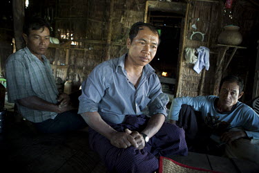 Tin Win Hlaing (41, centre) and Toe Naing (44, left) both impoverished farmers sit in Toe Naing's shack with other farm workers about an hour from Yangon.