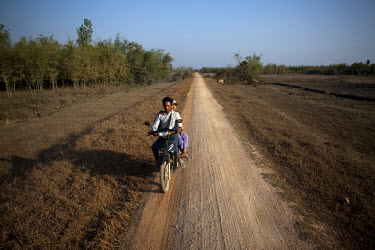Villagers ride a motorbike on a dusty road leading to NLD leader Aung San Suu Kyi's new constituency near Wah Thi Ka.