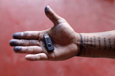 Roni Surui, sporting tribal body paintings, holds a flash drive in his palm in the village of Lapetanha, in the Brazilian Amazon. He is a chief of the Surui (Paiter) tribe. The Surui had had no contac...