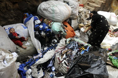 A young boy lies on bags full of rubbish, while his mother sorts through the piles of waste. The rubbish collectors, referred to as the Zabaleen, are a minority group of Coptic Christians who have wor...