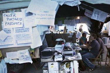 The interior of a tent, complete with computers, and printers. Signs and papers litter the walls inside and out. In May 2012, following a worsening financial crisis and a deepening recession in Spain,...