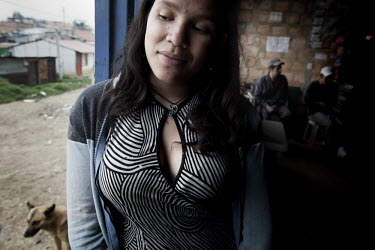 19 year old Yemini Esperanza Narbaes stands at the door to a bar in one of Bogota's poorest and most dangerous neighborhoods called Altos de la Florida. The area lies by a hillside on a dirt-road and...