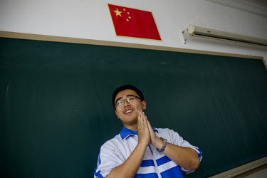 A student speaks before his class during an English lesson at the Beishida Erfuzhong (Middle School Number Two). A Chinese flag is visible above the blackboard.