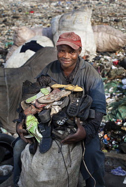 A man holds a pile of shoes and soles which he has found on the Olusosun rubbish dump in Lagos. The Olusosun dump is Nigeria's largest rubbish dump comprising over 100 acres of waste and is believed t...