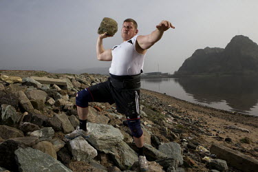 Neil Elliott holds up a rock on a beach near his home in Dumbarton. He competes in over 40 Highland Games and heavyweight events across the world throughout the summer.