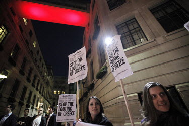 A group of demonstrators gather outside the London School of Economics (LSE) holding signs saying, 'STOP THE LOOTING OF GREECE'.