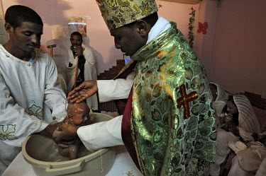 Eritrean asylum seekers conduct a baptism ceremony for Solomon, at a side room of their makeshift church.