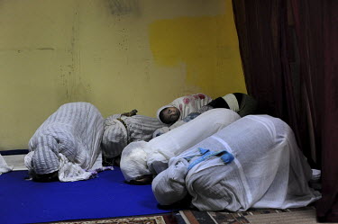 A girl lays on her mother's back as Eritrean women conduct a prayer at their makeshift church. Eritreans are the largest community of asylum seekers arriving in Israel since 2006.