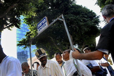 Eritreans walk past an Israeli security man, during a large procession in which hundreds of African asylum seekers marched through the streets of Tel Aviv, calling Israeli authorities to grant them as...