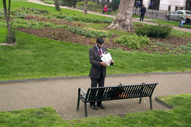 A man stands by a bench in Grosvenor Gardens along the number 38 London bus route, which runs from Victoria to Clapton Pond.