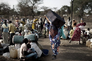 A woman walks through a crowd of newly arrived people in Doro refugee camp, carrying a suitcase stuffed with all she could carry on fleeing her home. More than 500,000 people have fled from Sudan into...