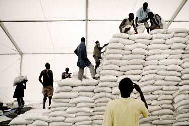 Men stack sacks of lentils in a World Food Programme (WFP) food distribution point in the Jammam refugee camp.