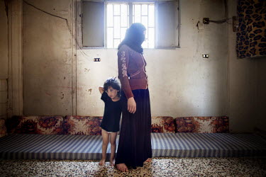 28 year old Rana Alkassem Alkhaled with her three year old child Omar. They live in a narrow one room apartment together with 10 other children and a total of five adults. 'My husband used to sell fru...