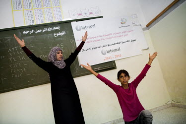 Teacher, Inaam Mahmoud Abu-Suawein, does stretching exercises with a pupil during a class at the Nour El Marifa School for Special Needs.