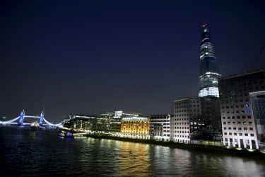 A view from the north side of the River Thames, London, to buildings on the south bank, with the Shard, rising 310 metres, in the centre and to the left, illuminated in blue, is Tower Bridge.