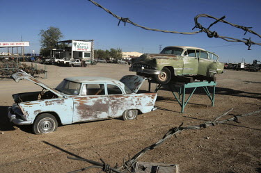 A junk yard with old cars, some old times are displayed as publicity.