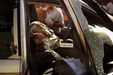 A murder victim lies in a truck as a policeman investigates. The death was probably linked with drug trafficking.
