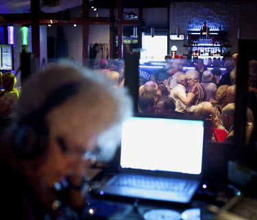 Couples dance as Wika Szmyt, a 74 year old DJ, the oldest in the country, stands at a mixing desk playing music at the Bolek Club. She runs the club night, which is mainly frequented by pensioners, tw...
