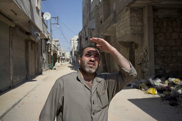 A man looks up as a Syrian Airforce fighter jet circles over a nearby Free Syrian Army (FSA) command centre in Aleppo. The command centre was bombed the following day killing nearby civilians in a bak...