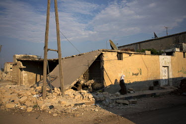 A woman walks past a damaged house in the recently liberated town of Azaz near the Turkish border.
