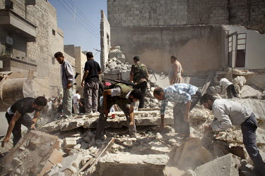 Free Syrian Army (FSA) fighters and civilians search for bodies or wounded amongst the rubble of a residential home destroyed by two bombs dropped from Syrian Airforce fighter jets that were targeting...