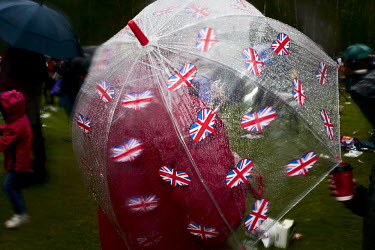 A person shelters beneath an umbrella adorned with Union Jack flags during Queen Elizabeth II Diamond Jubilee celebrations in central London.