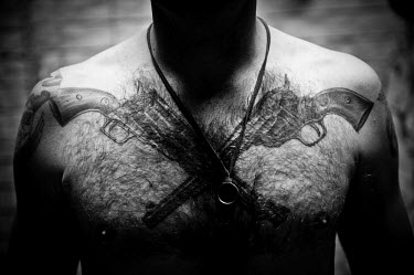 A US marine, at the military base in Garmsir, displays a tattoo on his chest depicting two crossed pistols. at the base in Garmsir.