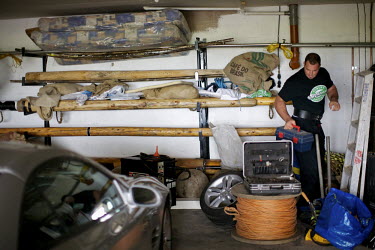 Gregor Edmunds, former world caber tossing champion and World Highland Games Champion in 2007 sorts through his garage at his home. He has stored some cabers on a wall rack behind him.