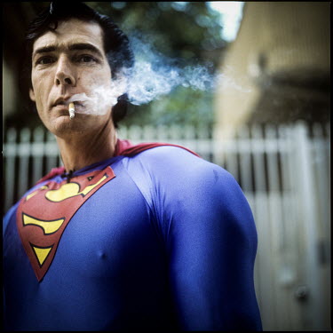 45 year old Christopher Dennis smokes as he poses in a Superman costume on Hollywood Boulevard. He has been entertaining tourists, posing for photographs with them for the last 19 years.