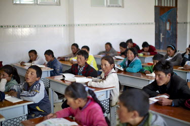 Children in an English class at the middle school in the county town of Zhiduo. Hundreds of nomadic families are paid and provided with a new home to bring their children for education. The resettleme...
