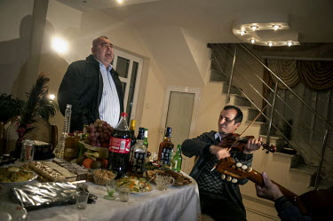 Onize, one of the most influential businessmen in Certeze village, sings a song at a celebration in the village. Two musicians accompany him on guitar and violin.