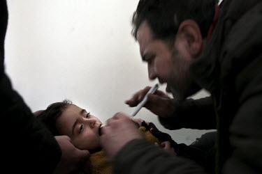 Dr Rami, who lived in Leicester in the UK until recently, treats a child in the basement of the hospital where he works in the town of Salma near the front line between the Free Syrian Army and govern...