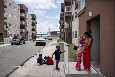 A woman and her children on a pavement outside a residential block in Maputo where mostly middle class families live. In the background the new football stadium built by a Chinese company. Mozambique'...