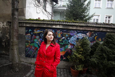 Oliwia Dabrowska, 24, who played the little girl in a red coat in Steven Spielberg's 1993 film "Schindler's List", poses by a mural depicting scenes from the "Fiddler on the Roof" story in the Kazimie...