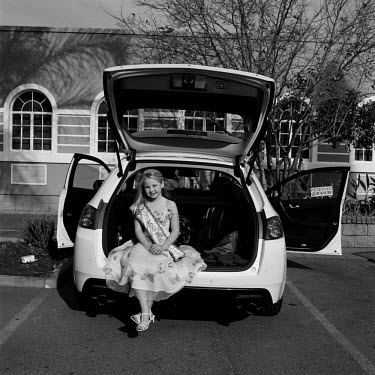 Courtney, Miss Petite sits in the hatch of a car outside Brakpan Town Hall.