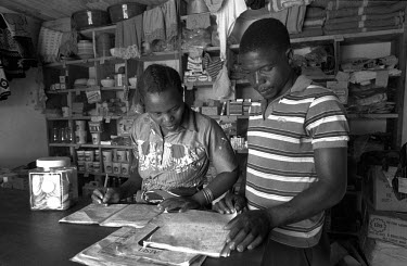 A couple study their accounts on the counter of their village shop.