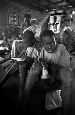 A group of boys take notes during a school class held in a machine room.