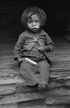 A young girl eating a radish.