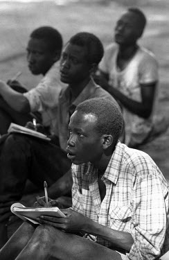 Dinka pupils listen attentively to their teacher at an outdoor school in the Kakuma Refugee Camp.
