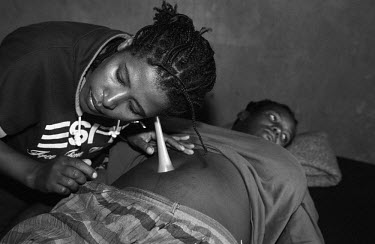 A midwife, working in a health clinic at the Kakuma Refugee Camp, uses a Pinard Stethoscope to listen to the heart beat of a pregnant Dinka woman's foetus.