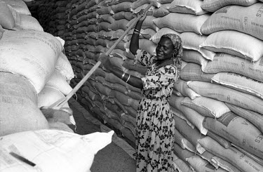A woman sweeps dust from sacks of sorghum flour in a warehouse storing food relief aid at the Kakuma Refugee Camp.
