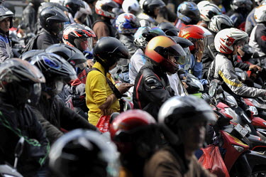 Woman passenger on a motorbike talks on her mobile phone amid a sea of similarly incoming motorcycle commuters. With 10-plus million people living in the capital - 25 million, if the Greater Metropoli...