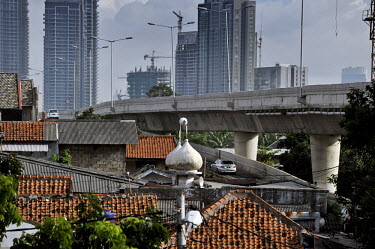 A newly completed elevated road cuts through the south Jakarta skyline, separating the village-like atmosphere of "old" Jakarta (with its mosques and tile-roofed homes) from the skyscrapers of "new" J...