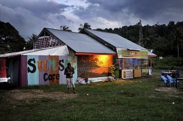 A man uses his mobile phone outside the 'Sunset Cafe', at dusk, in Sabang, the northernmost town in all of Indonesia, and capital of Weh Island. Following a peace deal with the central government Aceh...