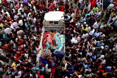 A crowd of people gathers around a pick up truck carrying the bodies of garment workers crushed to death in the collapsed Rana Plaza complex in Savar. The 8 storey building, which housed a number of g...