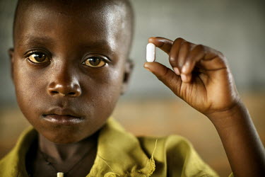A young boy at Nkanga School holds a tablet containing some of the medication he needs to treat and prevent intestinal worms and schistosomiasis (River Blindness). It was proscribed as part of a natio...