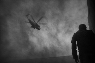 A man stands  helicopter departs the base in Garmsir carrying US Marines and ANA (Afghan National Army) soldiers.
